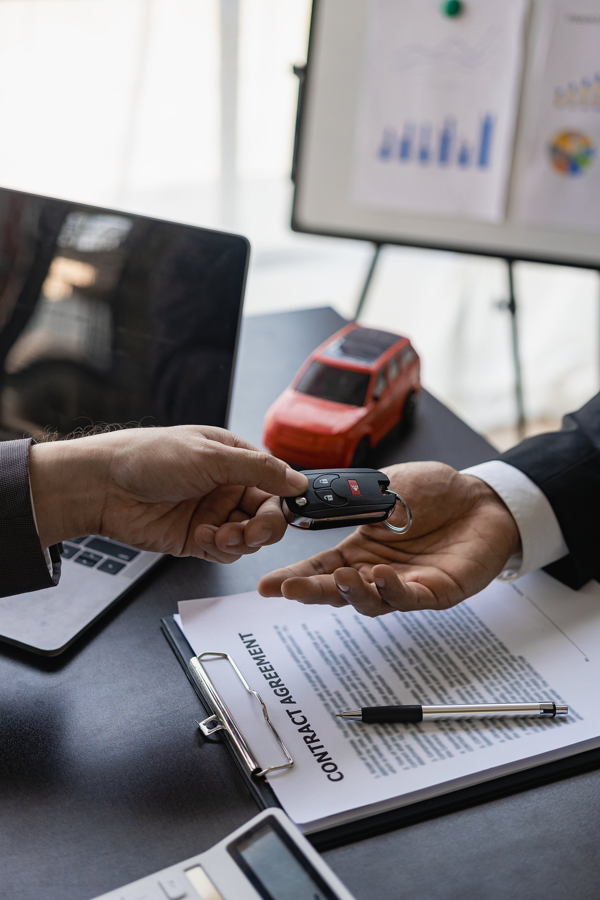 Young salesman holding car keys in hands of car rental business customer sell or buy services Asian male sales representative sells important cars to client tenants.